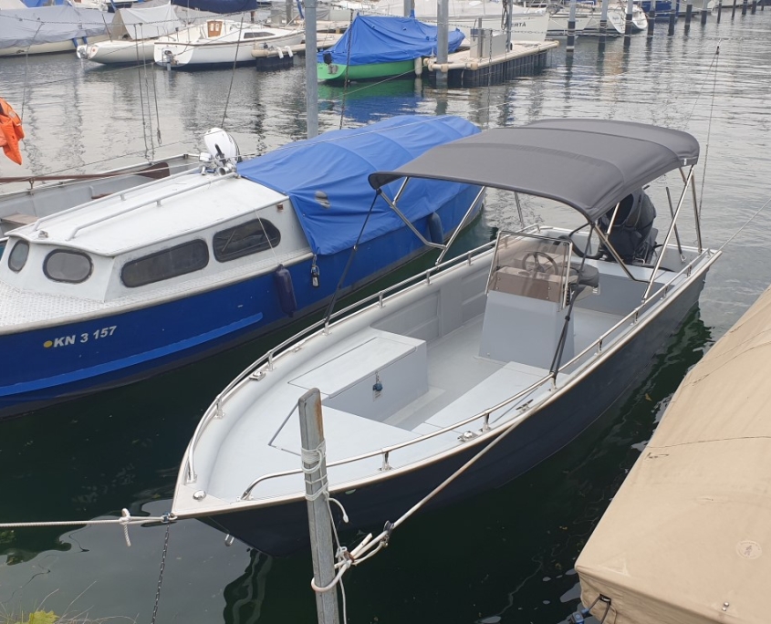 Bimini Top 6 Offenes Motorboot mit grauem Bimini-Top im Bootshafen