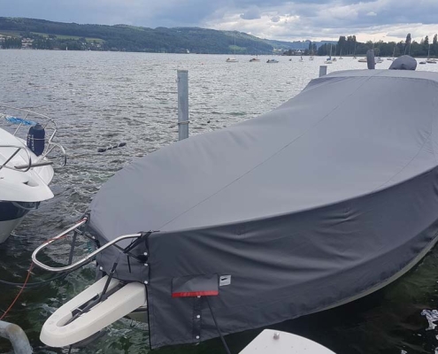 Persenning 1 Motorboot mit grauer Ganzpersenning am Steg vor Seepanorama