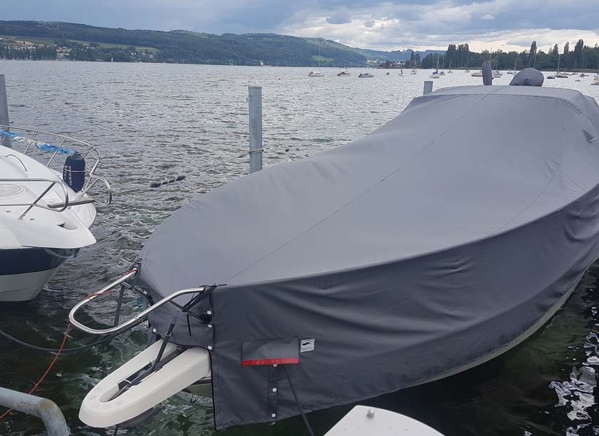 Persenning 1 Motorboot mit grauer Ganzpersenning am Steg vor Seepanorama