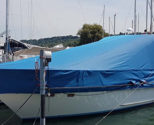 Persenning 2 Motoryacht mit blauer Persenning im Bootshafen