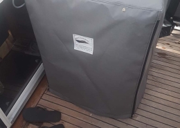 Sonderanfertigung 5 Graue Schutzhaube nach Maß mit Bootssattlerei-Logo auf dem Teakdeck einer Yacht