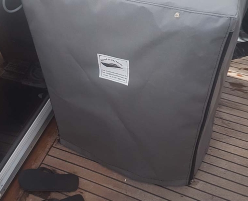 Sonderanfertigung 5 Graue Schutzhaube nach Maß mit Bootssattlerei-Logo auf dem Teakdeck einer Yacht
