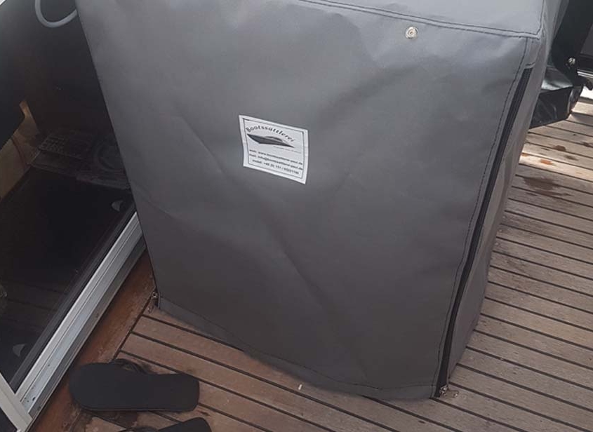 Sonderanfertigung 5 Graue Schutzhaube nach Maß mit Bootssattlerei-Logo auf dem Teakdeck einer Yacht