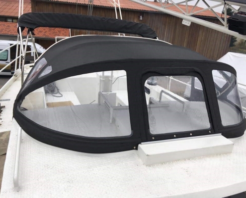 Sprayhood Galerie 2 Schwarze Sprayhood mit großen Klarsichtfenstern auf einem weißen Motorboot