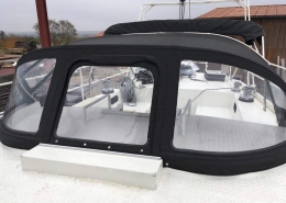 Sprayhood Galerie 7 Sprayhood mit drei Klarsichtfenstern auf weißem Motorboot vor der Werkstatt