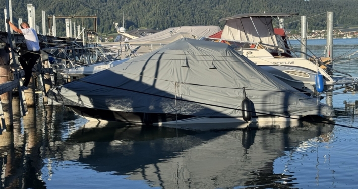 Graue Ganzpersenning über einem Motorboot am Steg